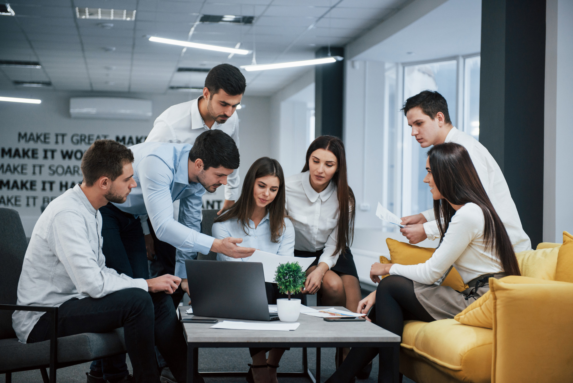 oficinistas reunidos entorno a un portatil discutiendo alguna idea